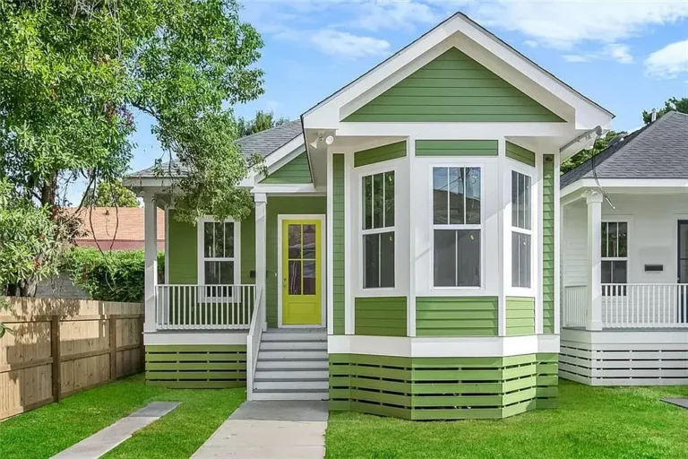 New-construction raised cottage in New Orleans built by DuCar Construction, with green lap siding, a bay window and a front porch