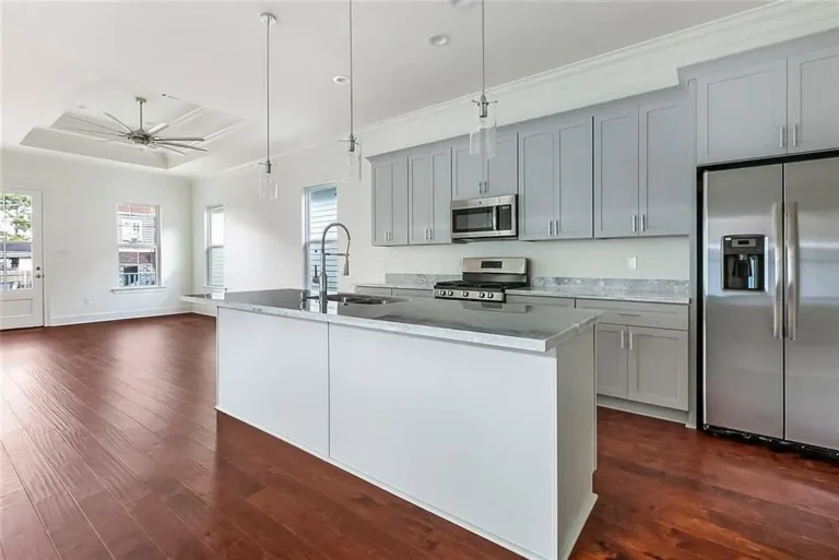 Kitchen in a DuCar new-construction home in New Orleans with gray shaker cabinets, marble-look counters and a large island