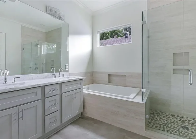 Primary bathroom with double vanity, soaking tub and glass shower in a DuCar new home in New Orleans
