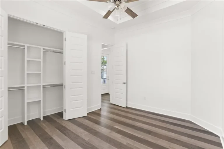 Bedroom with built-in closet shelving and a tray ceiling in a DuCar new home in New Orleans