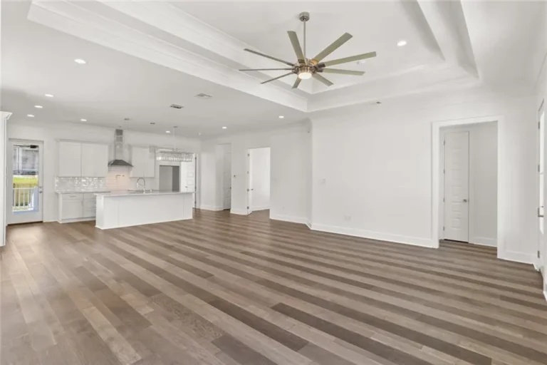 Open living, dining and kitchen with a tray ceiling in a four-bedroom DuCar new home in New Orleans