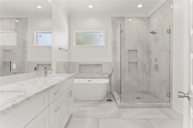 Primary bathroom with freestanding tub, glass shower and double vanity in a DuCar new home in New Orleans