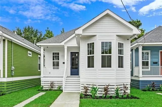 White raised cottage with a bay window and blue door, new construction by DuCar Construction in New Orleans
